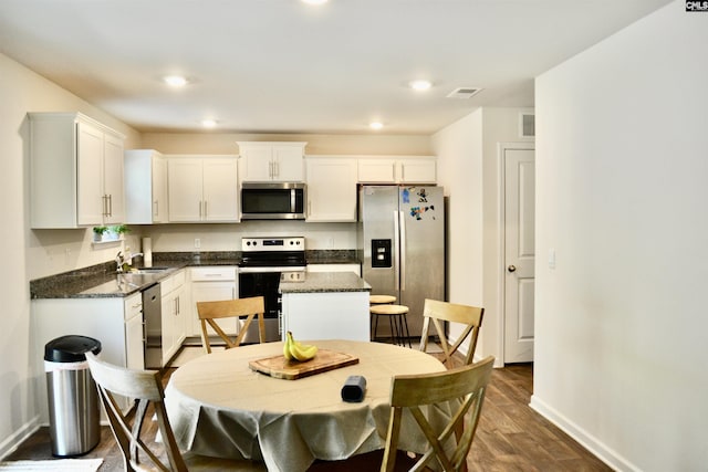 kitchen with white cabinetry, appliances with stainless steel finishes, baseboards, and dark wood finished floors