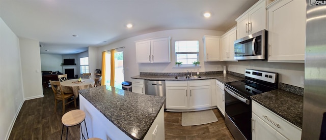 kitchen featuring appliances with stainless steel finishes, dark wood-style floors, plenty of natural light, and a kitchen island