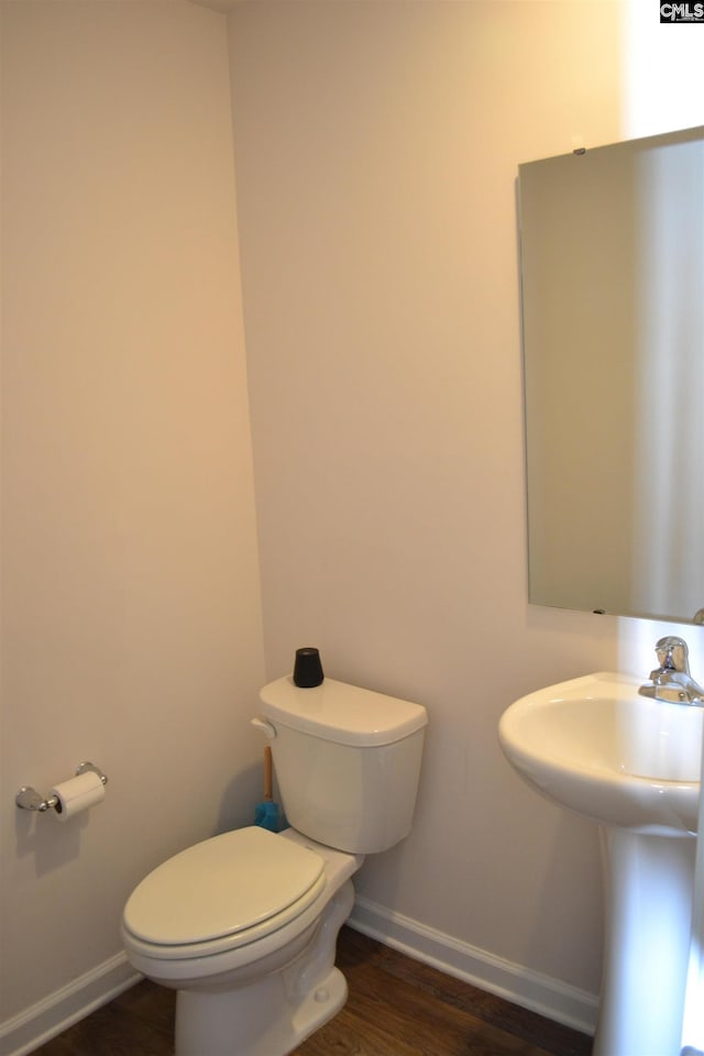 half bathroom with toilet, wood finished floors, and baseboards