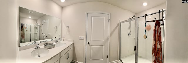 full bathroom with a shower stall, double vanity, baseboards, and a sink