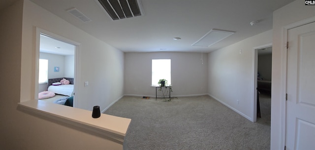 spare room with carpet flooring, visible vents, baseboards, and attic access