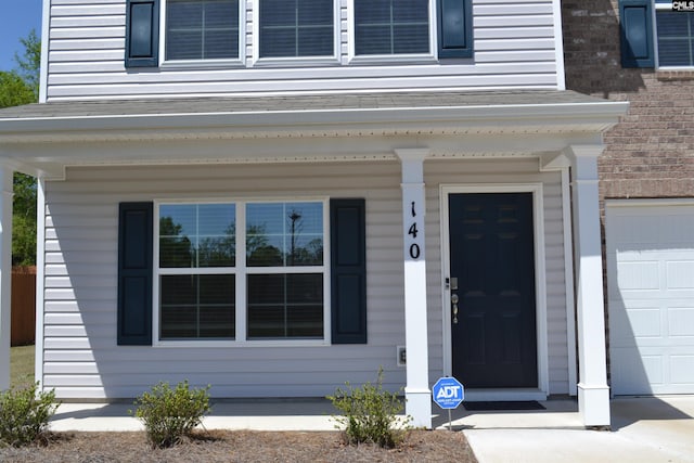 doorway to property featuring a porch and a garage