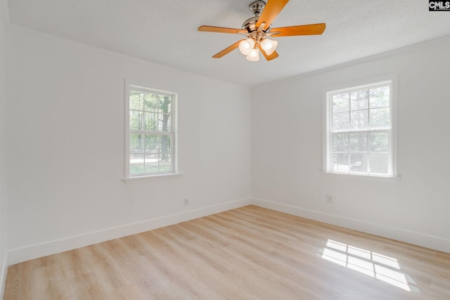 empty room with ornamental molding, baseboards, and light wood-type flooring