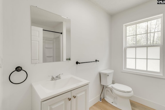 bathroom featuring toilet, baseboards, vanity, and a healthy amount of sunlight