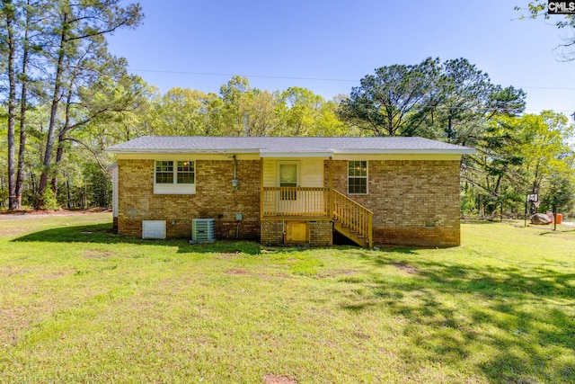 back of house featuring central AC, crawl space, brick siding, and a lawn