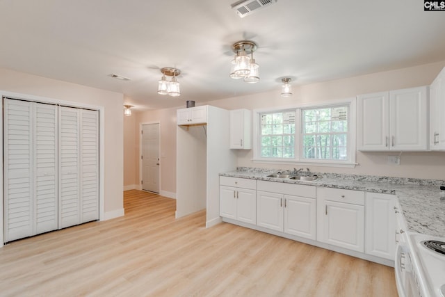 kitchen featuring stove, visible vents, light wood-type flooring, and a sink