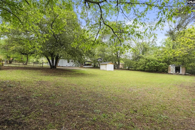 view of yard featuring an outbuilding, fence, and a storage unit