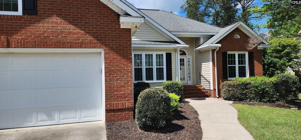 doorway to property with a garage, roof with shingles, brick siding, and concrete driveway