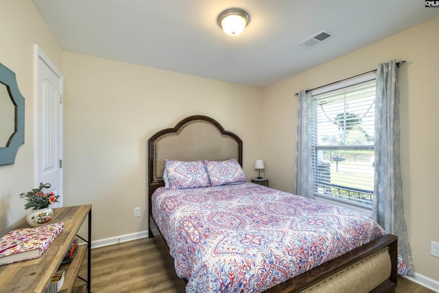 bedroom with visible vents, baseboards, and wood finished floors