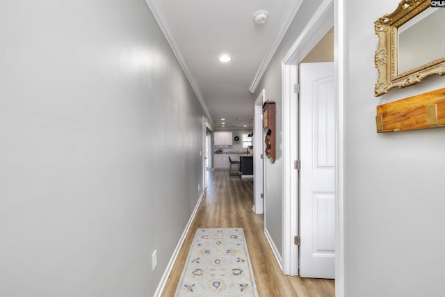 hallway featuring crown molding, light wood finished floors, baseboards, and recessed lighting
