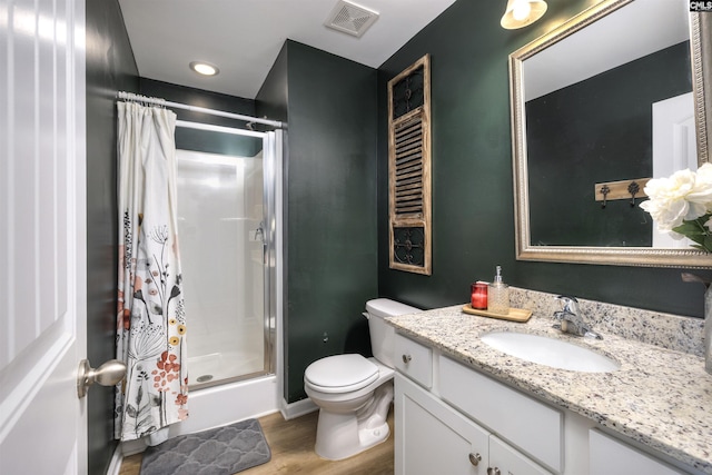 bathroom with visible vents, toilet, a shower stall, vanity, and wood finished floors