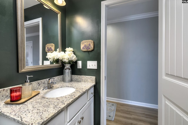 bathroom with vanity, baseboards, ornamental molding, and wood finished floors