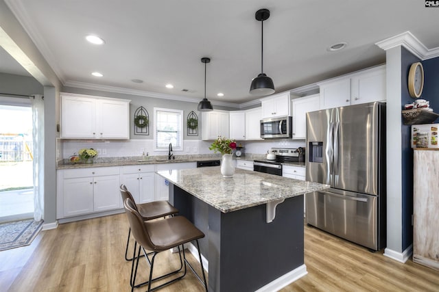 kitchen featuring white cabinets, a sink, light wood-type flooring, stainless steel appliances, and backsplash