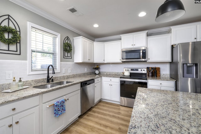 kitchen featuring ornamental molding, white cabinetry, visible vents, stainless steel appliances, and a sink