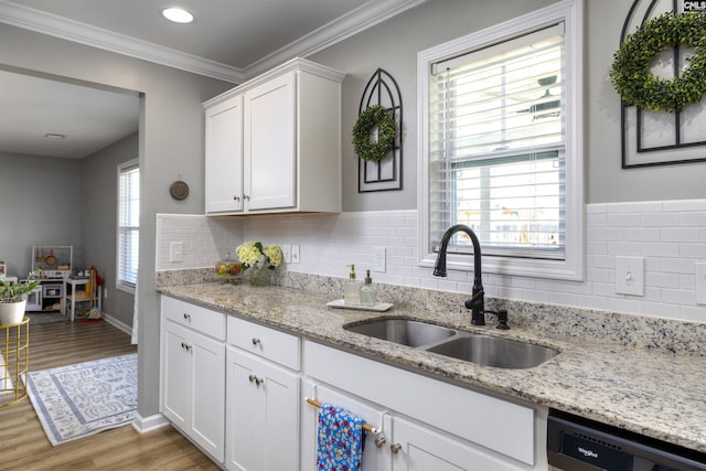 kitchen featuring white cabinets, dishwasher, a sink, ornamental molding, and light wood finished floors