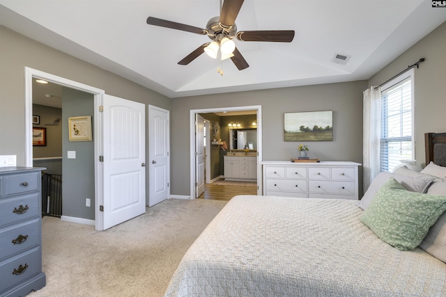 bedroom featuring visible vents, baseboards, ensuite bathroom, vaulted ceiling, and light carpet
