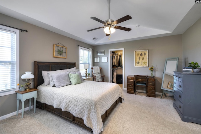 bedroom featuring a closet, baseboards, a spacious closet, ceiling fan, and light carpet