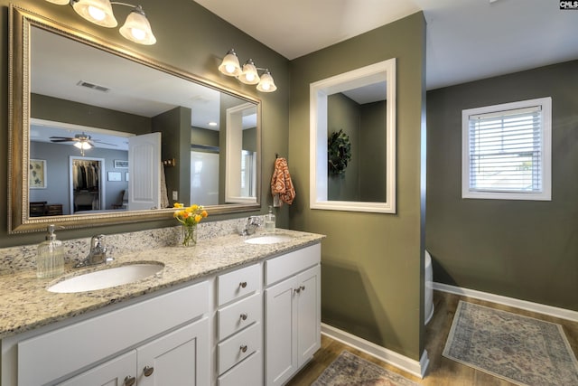 bathroom with baseboards, wood finished floors, a sink, and visible vents