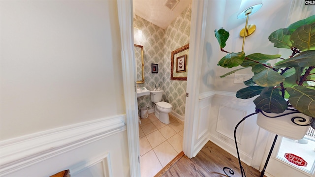 bathroom with toilet, wallpapered walls, visible vents, and a wainscoted wall