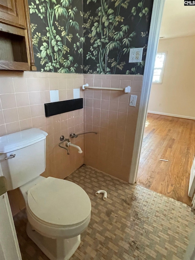 bathroom with tile walls, wainscoting, wood finished floors, toilet, and wallpapered walls