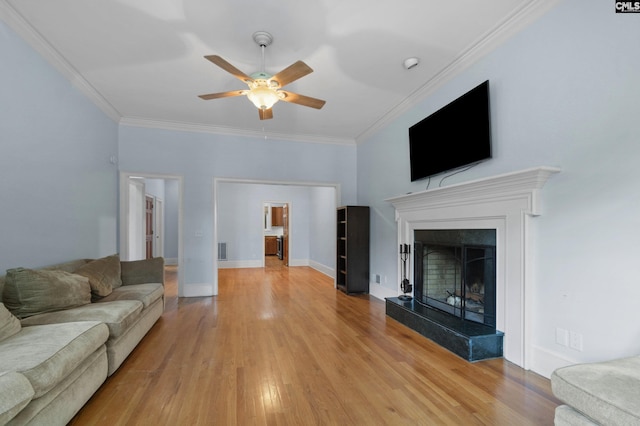 living room with a fireplace, light wood-type flooring, crown molding, and ceiling fan