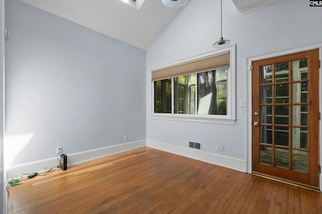 unfurnished room with hardwood / wood-style floors, high vaulted ceiling, baseboards, and visible vents