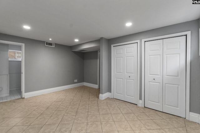 finished below grade area featuring visible vents, baseboards, recessed lighting, and light tile patterned floors