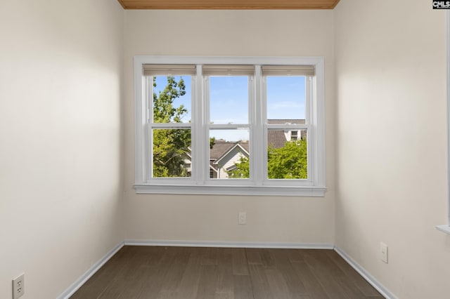 spare room with plenty of natural light, baseboards, and dark wood finished floors