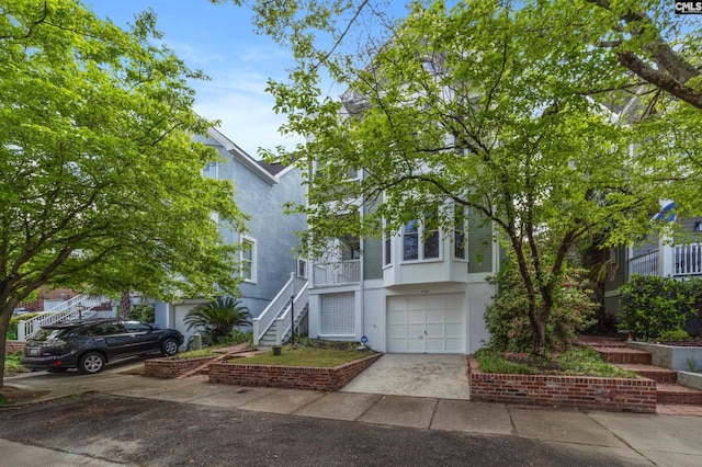 view of front of house featuring a garage, stucco siding, driveway, and stairway