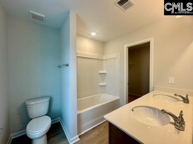 2022 Skyline Rd, Columbia, SC 29229 - full bath with wood finished floors, toilet, double vanity, baseboards, and shower / bathtub combination