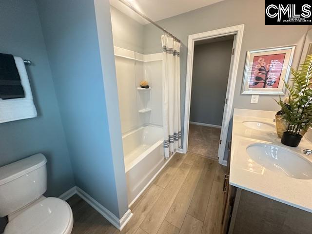 2022 Skyline Rd, Columbia, SC 29229 - full bath featuring wood finished floors, toilet, baseboards, shower / tub combo with curtain, and double vanity