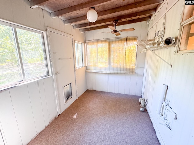 unfurnished sunroom featuring beamed ceiling and plenty of natural light