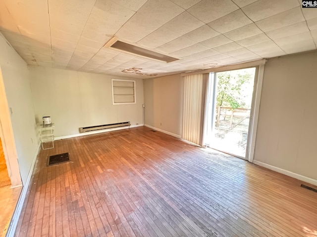 unfurnished room with wood-type flooring, baseboard heating, and visible vents