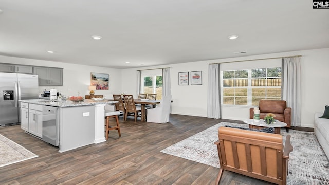 kitchen with open floor plan, dark wood-type flooring, a kitchen island with sink, a breakfast bar area, and stainless steel appliances