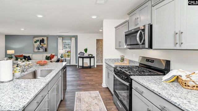 kitchen featuring recessed lighting, a sink, stainless steel appliances, gray cabinetry, and dark wood-style floors