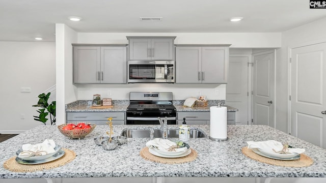 kitchen featuring light stone counters, gray cabinetry, and stainless steel appliances