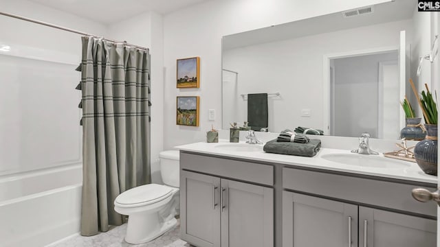 bathroom with toilet, double vanity, a sink, and visible vents