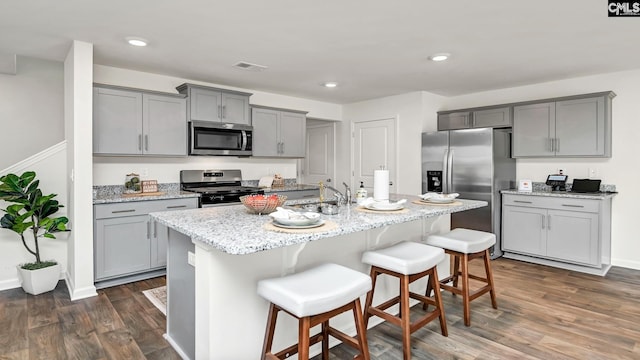 kitchen with gray cabinetry, dark wood-type flooring, a sink, and appliances with stainless steel finishes