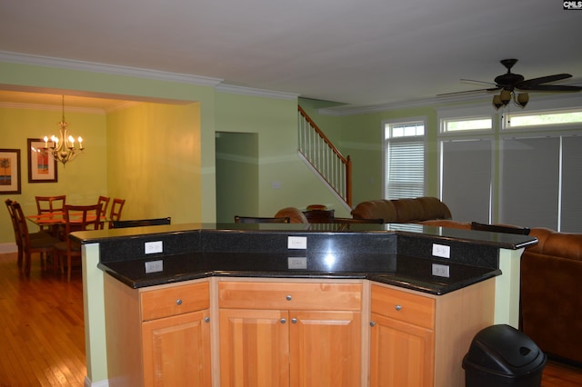 kitchen featuring crown molding, ceiling fan with notable chandelier, a kitchen island, wood finished floors, and open floor plan