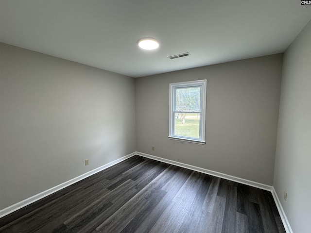 spare room featuring dark wood-type flooring, baseboards, and visible vents