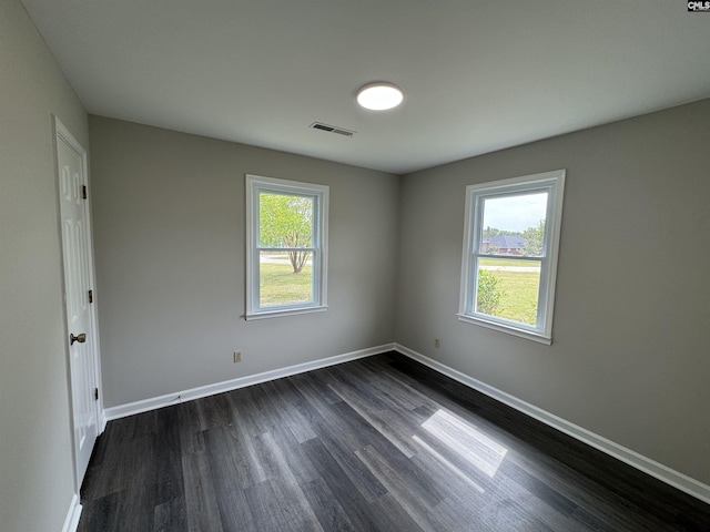 unfurnished room featuring visible vents, baseboards, and dark wood-style floors