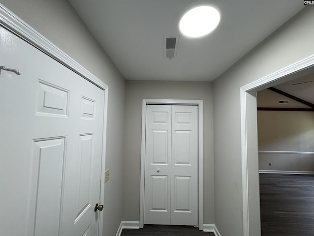 hall featuring dark wood-style flooring, baseboards, and visible vents