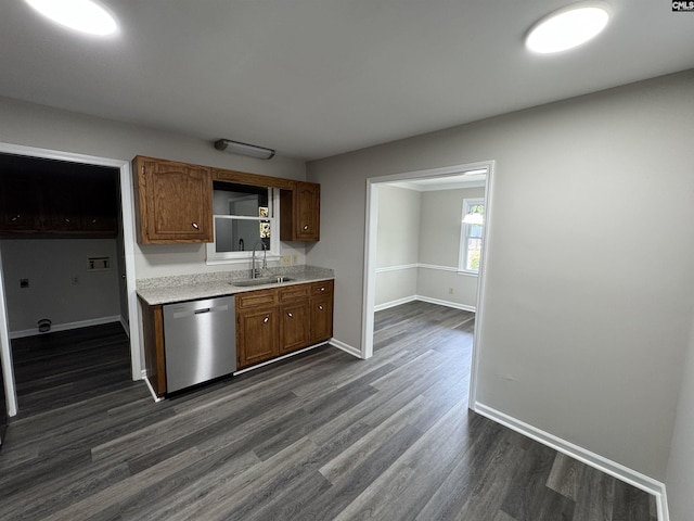 kitchen featuring baseboards, dishwasher, a sink, light countertops, and dark wood-type flooring
