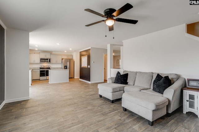 living area with recessed lighting, light wood-style floors, baseboards, and ceiling fan