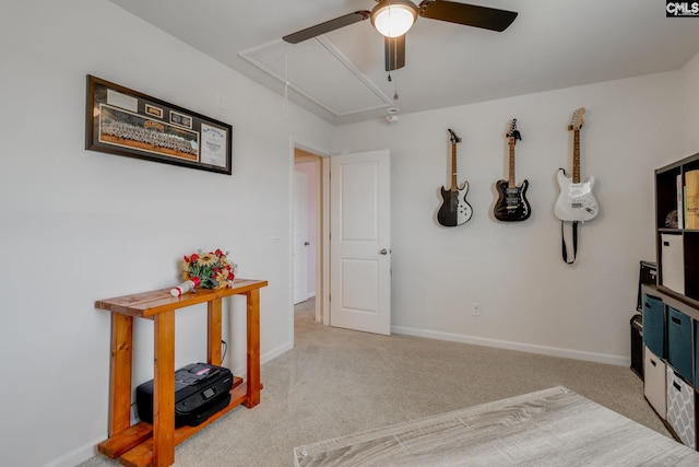 interior space featuring baseboards, attic access, ceiling fan, and carpet