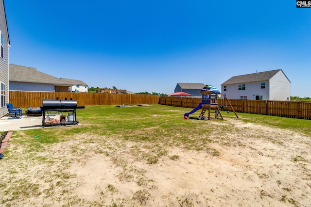 view of yard featuring a patio area, a fenced backyard, and a playground