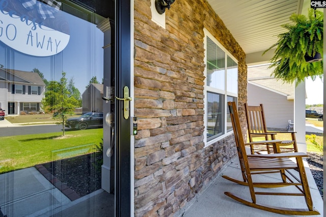 property entrance with a porch and stone siding