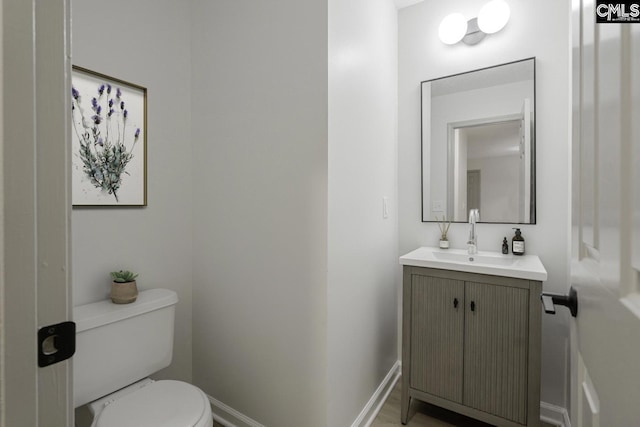 bathroom with toilet, vanity, and baseboards
