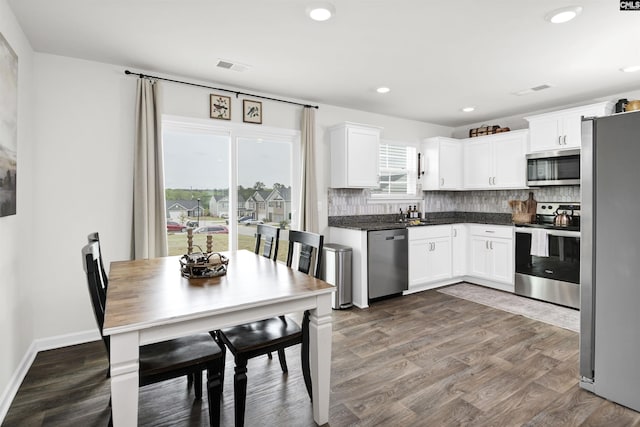 kitchen featuring tasteful backsplash, white cabinets, dark wood-type flooring, visible vents, and stainless steel appliances