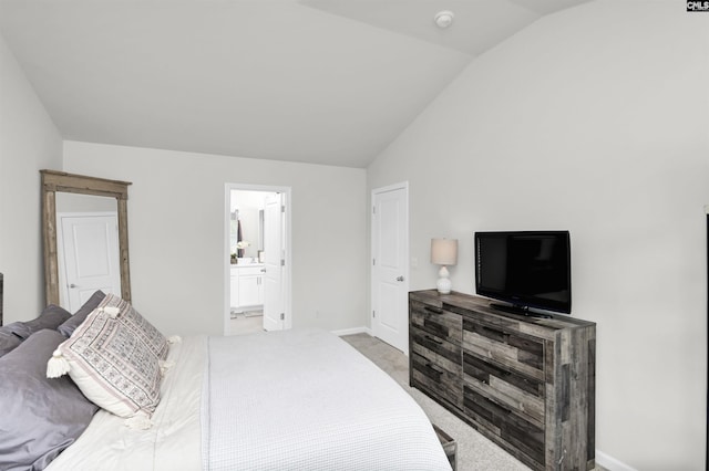 carpeted bedroom featuring baseboards, lofted ceiling, and ensuite bath